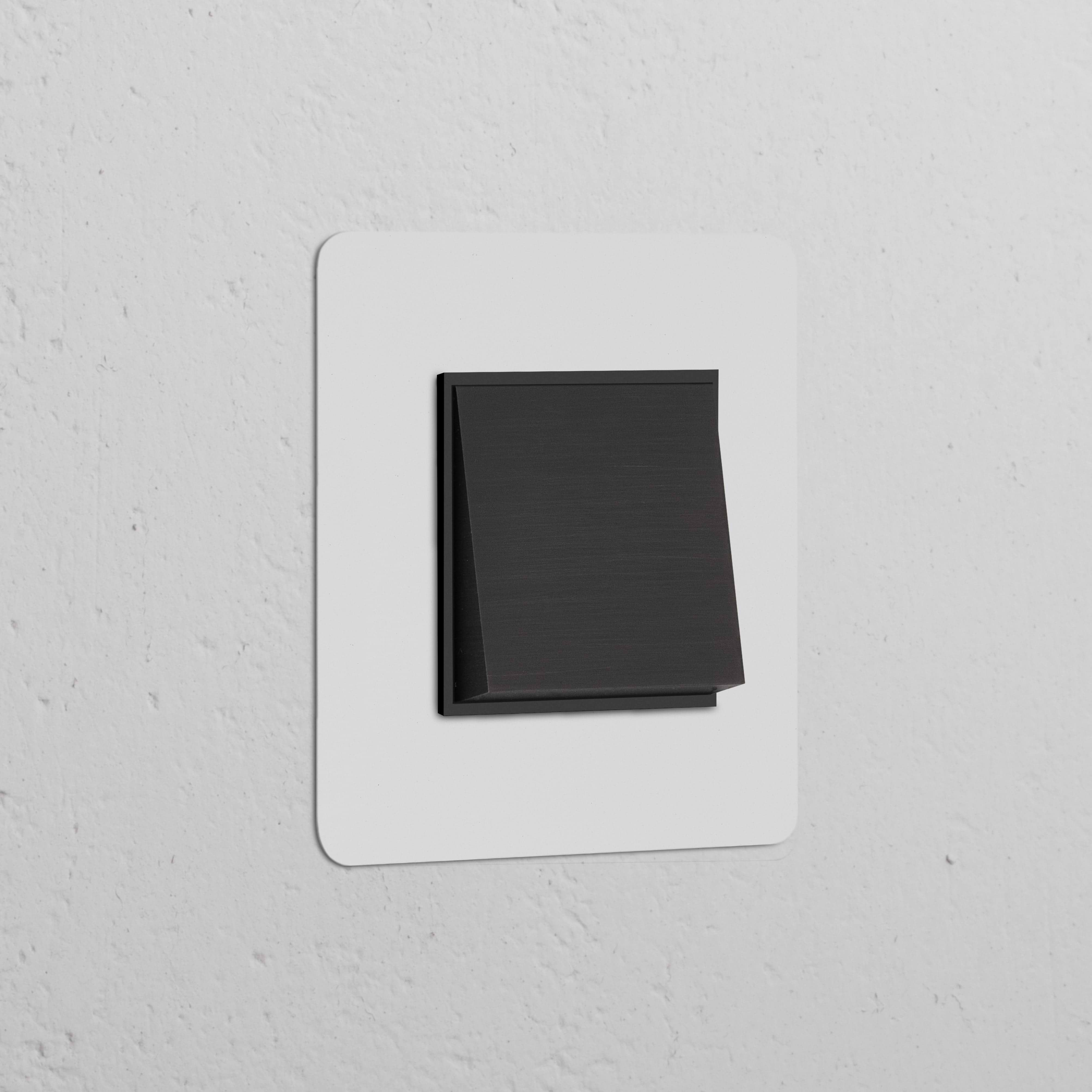 Single Rocker Switch (Int) in paintable bronze black on a white wall, offering customizable style and function.