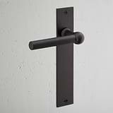 Harper Long Plate Sprung Door Handle Bronze Finish on White Background at an Angle