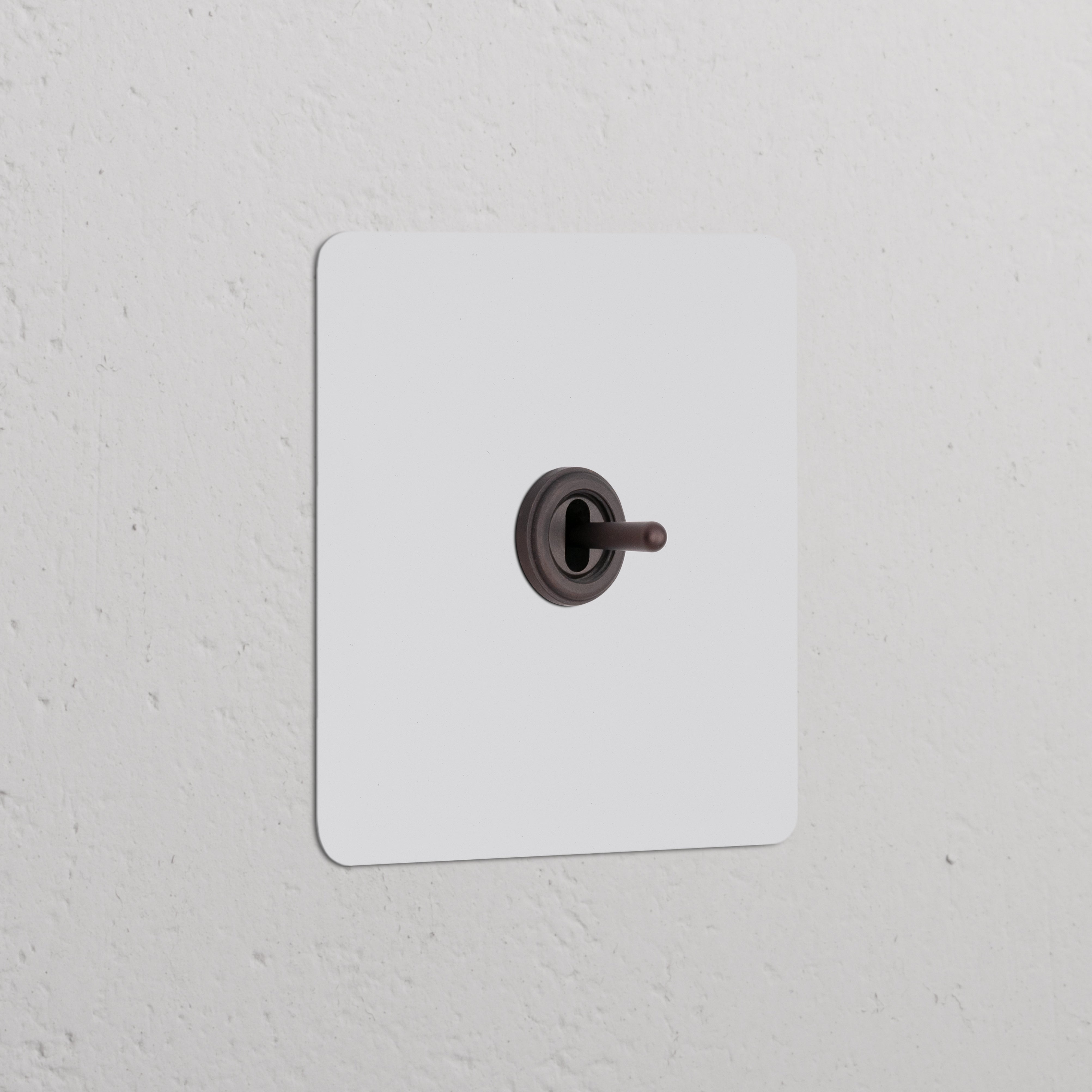 Single Toggle Switch in paintable bronze finish on a textured white wall, ideal for sleek and elegant decor.