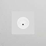 Single Swiss Type J Power Module Round socket, paintable white, blends into the textured white wall.