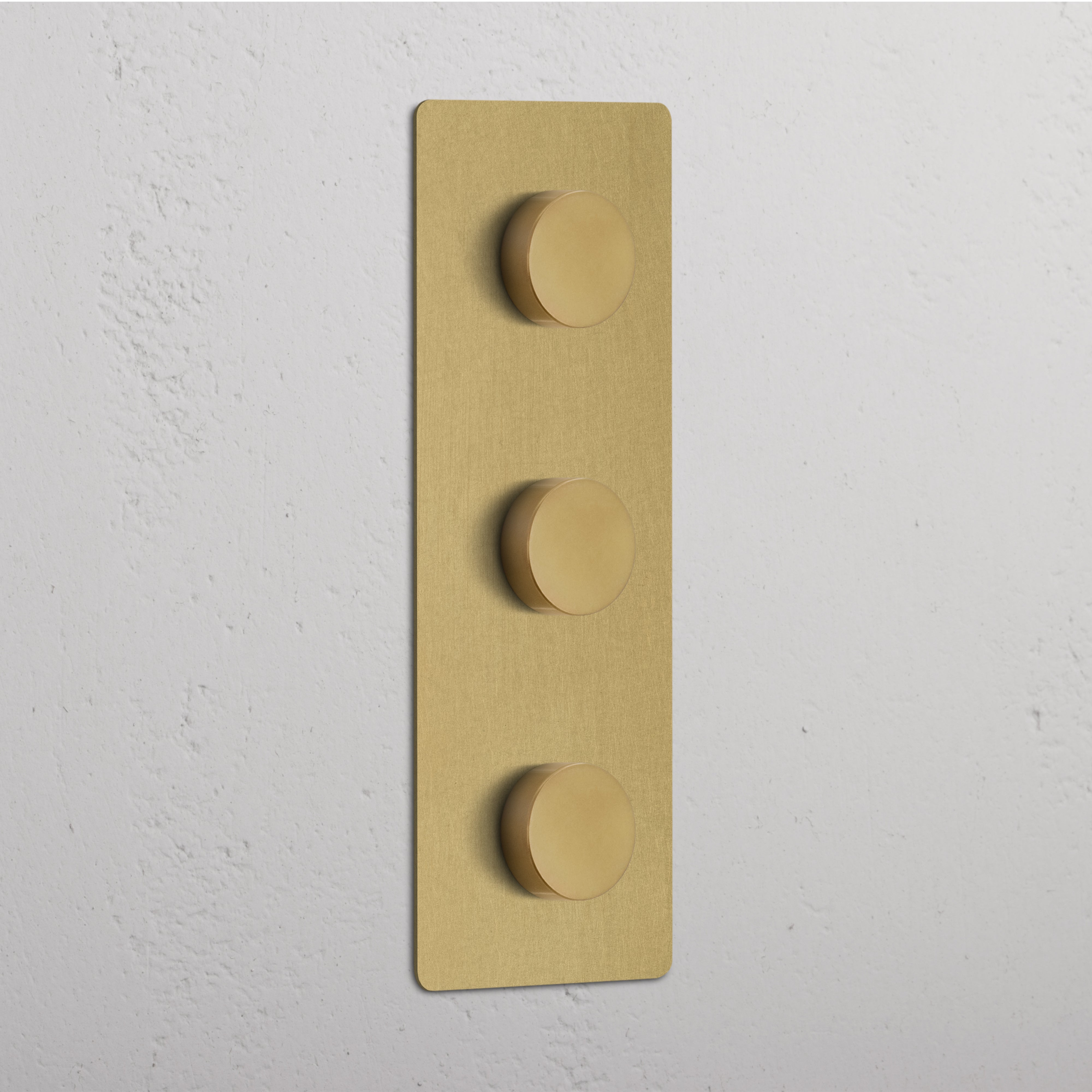 Antique Brass Triple 3x Vertical Multiway Dimmer Switch with three round knobs on a white textured wall.