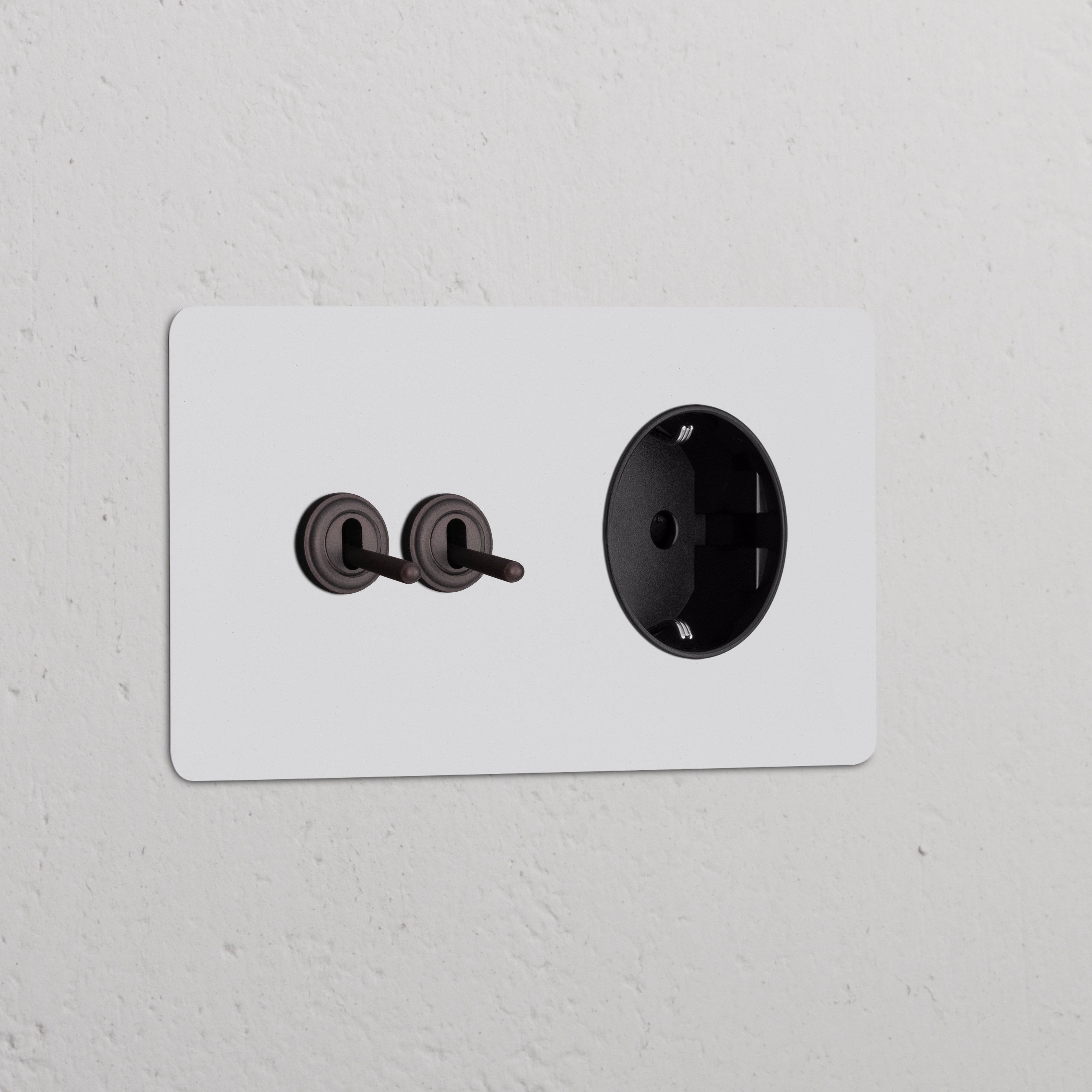 Paintable bronze black double 2x toggle switch with Schuko Type F power module on a white wall.