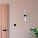 Claremont Medium Wall Light Fluted Glass in Bronze affixed to a wall with a Bronze Light Switch next to a wooden door and plant