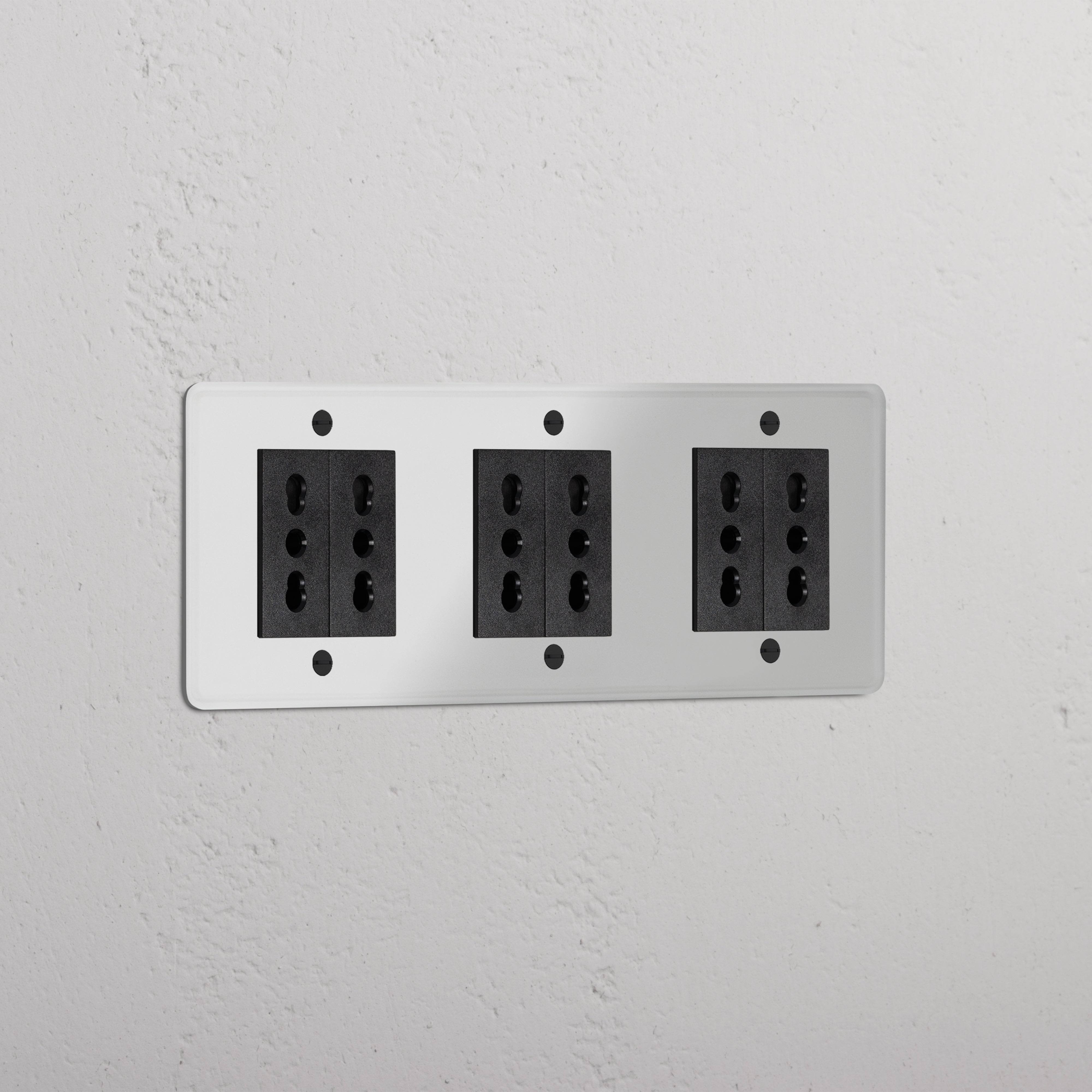 Triple 6x Bipasso Module - Clear Black with three multi-socket outlets against a white textured wall.