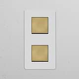 Double 2x vertical rocker switch in paintable antique brass on a white wall, suitable for elegant décor.
