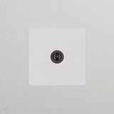 Single toggle switch in paintable bronze finish on a textured wall, designed for single switches and dimmers.