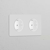Double 2x Schuko Type F power module in paintable white, designed as a round dual socket for wall installation.