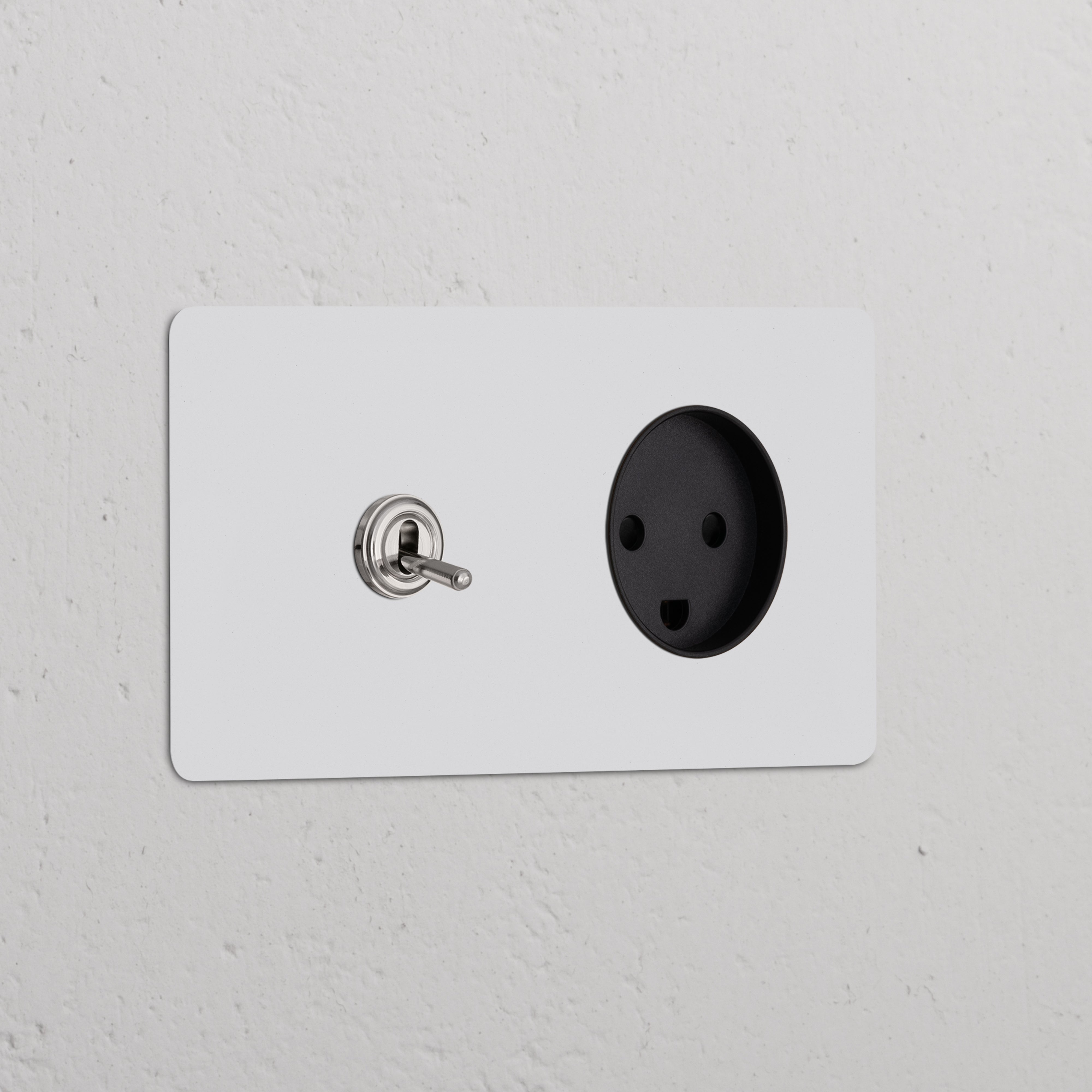 Double toggle switch and Danish Type K power module in polished nickel-black finish on a white textured wall.