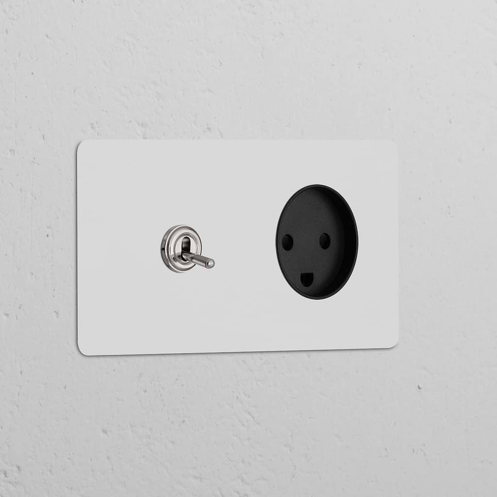 Double toggle switch and Danish Type K power module in polished nickel-black finish on a white textured wall.