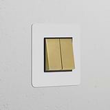 Single 2x Rocker Switch in paintable antique brass black finish on a white textured wall.