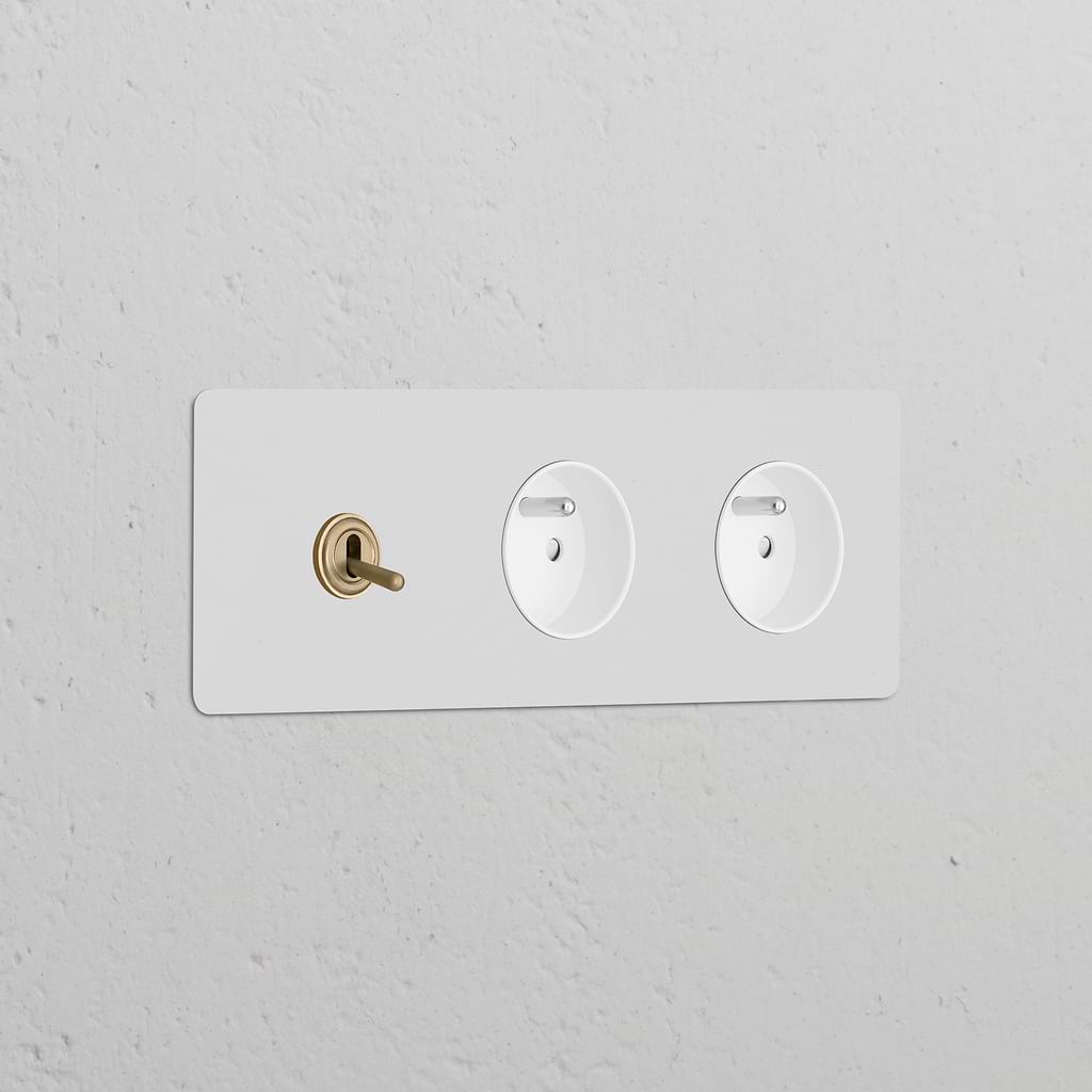 Triple sockets with triple toggle switch and 2 Type E modules in paintable antique brass white on a textured wall.