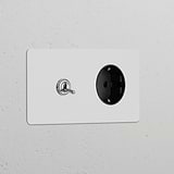 Double toggle switch and Schuko Type F power module in paintable polished nickel black on a white wall.