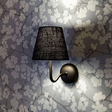 Malvern Medium Wall Light Basalt Grey - Bronze affixed to a floral wallpapered wall and turned ON