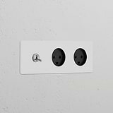 Triple toggle switch and two Danish Type K power modules in paintable polished nickel black on a white wall.