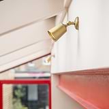 Antique Brass Bayliss Single 50mm Spotlight fitted  to a white wall on the right with red metal beam beneath. 
