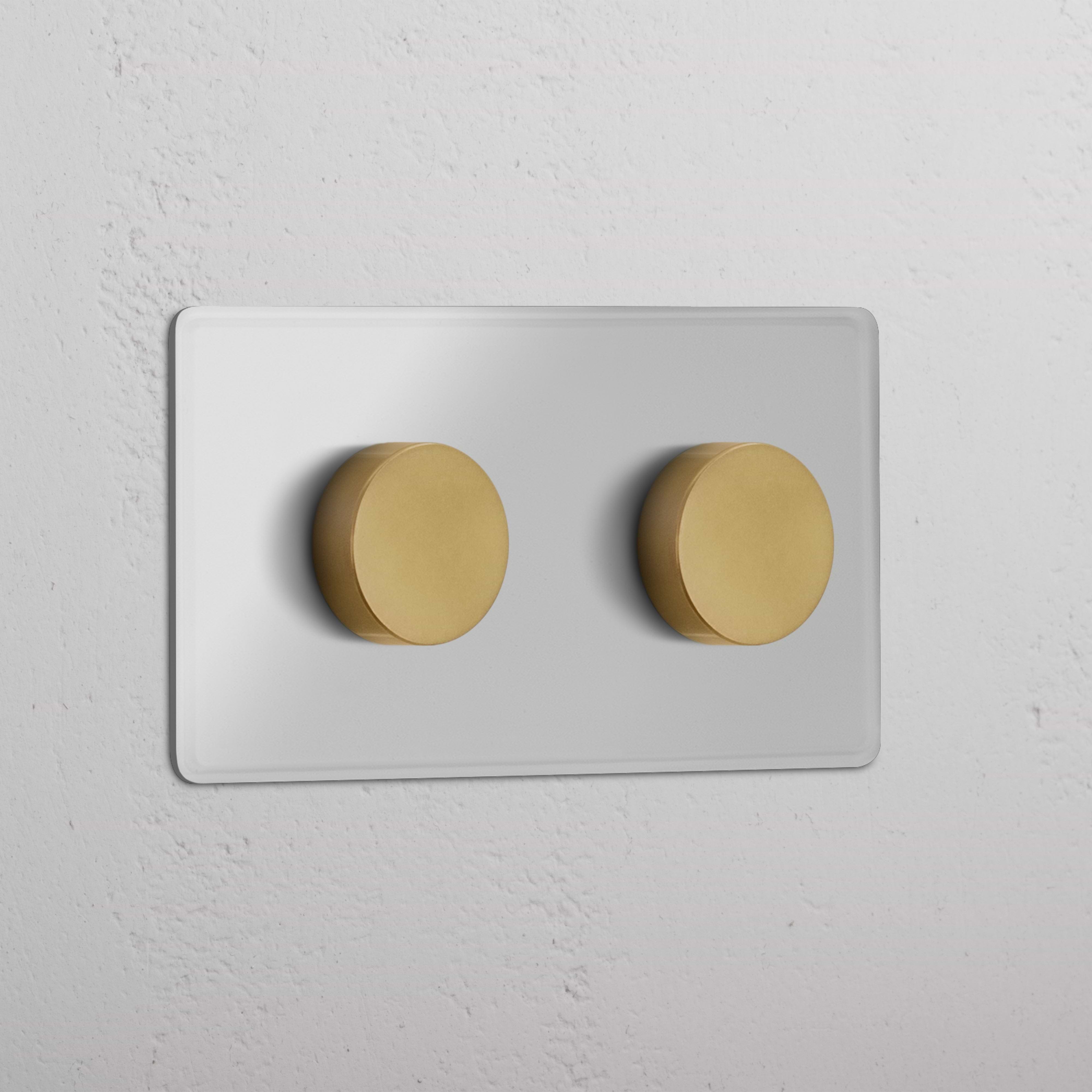 Double 2x multiway dimmer switch with clear antique brass knobs on a white wall plate.