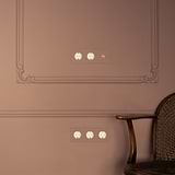 Triple toggle switch with 2x Schuko Type F power module, paintable antique brass white finish on a brown wall.