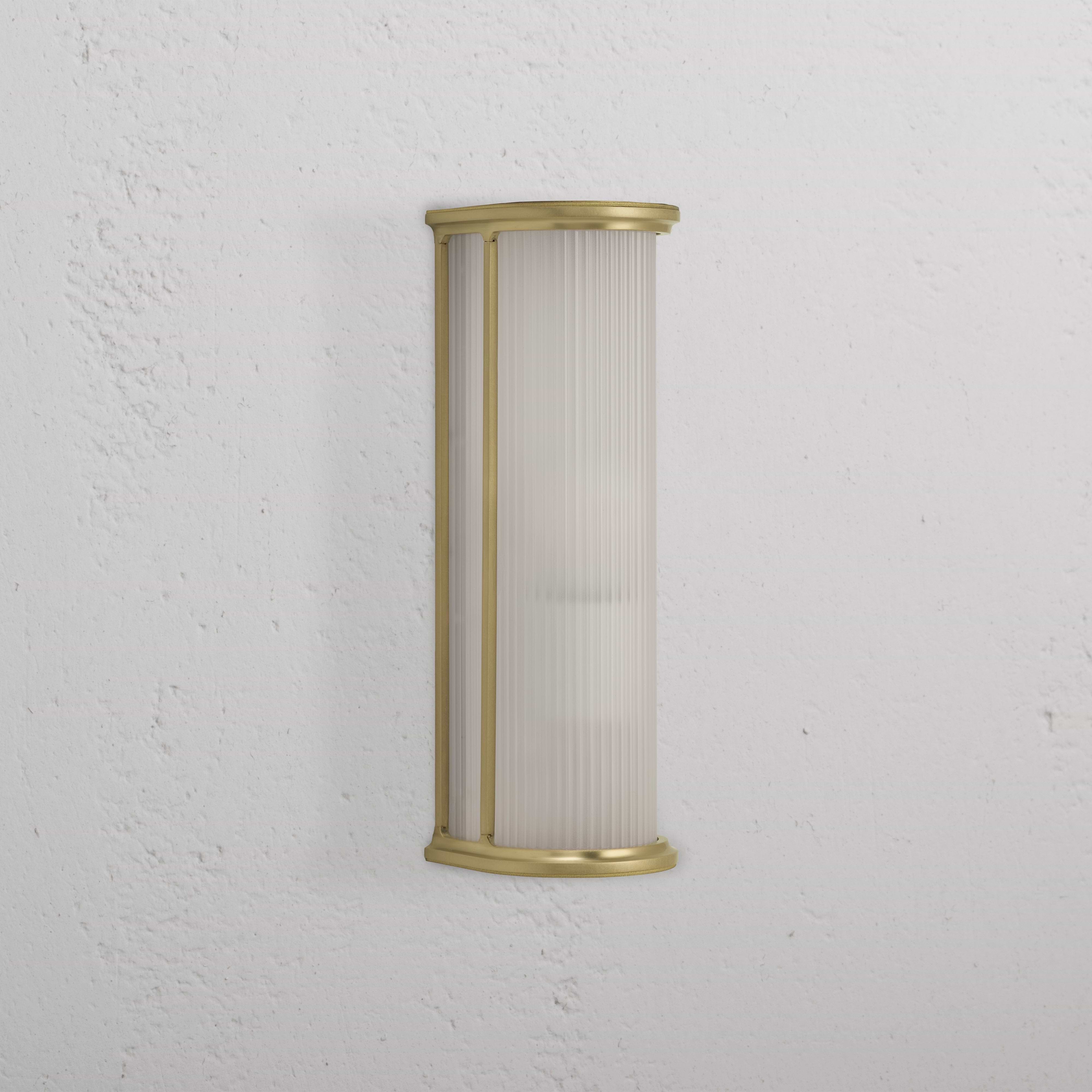 Medium wall light featuring fluted frosted glass and antique brass frame, mounted on a white textured wall.