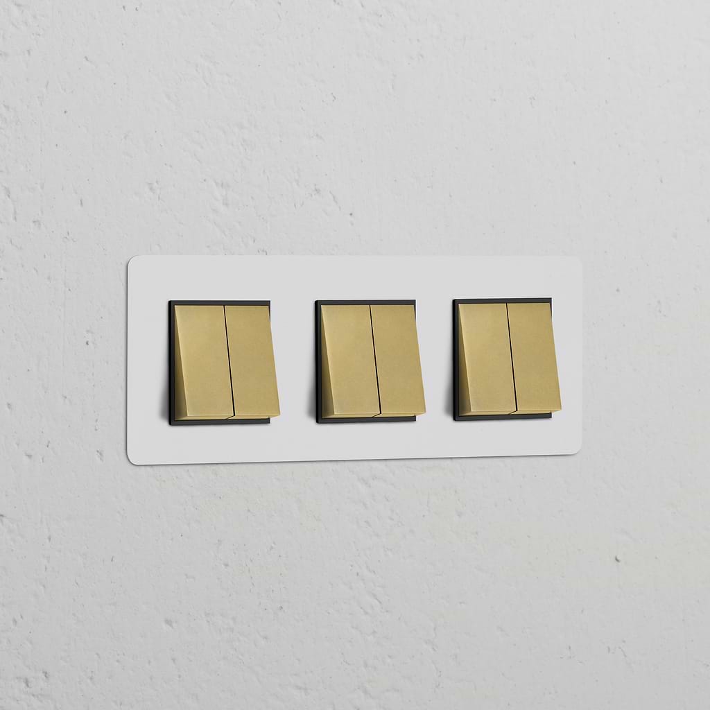 Triple 6x Rocker Switch in paintable antique brass black finish, mounted on a white wall.