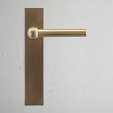 Harper Long Plate Fixed Door Handle Antique Brass Finish on White Background Front Facing