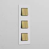 Triple 6x vertical rocker switch in paintable antique brass black on a white wall.