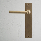 Harper Long Plate Sprung Door Handle Antique Brass Finish on White Background right Facing Front View