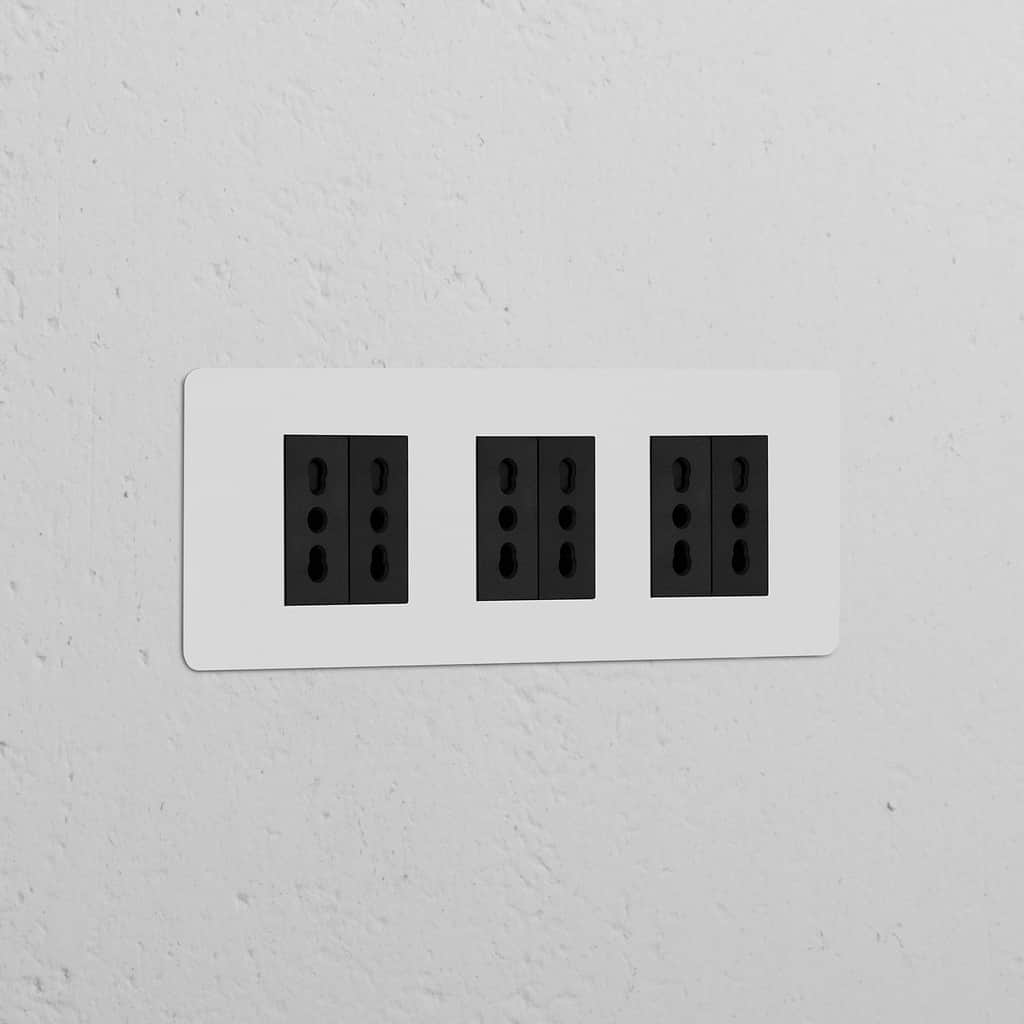 Paintable black Triple 6x Bipasso Power Module with triple sockets on a wall, blending functionality and style.