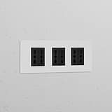 Paintable black Triple 6x Bipasso Power Module with triple sockets on a wall, blending functionality and style.