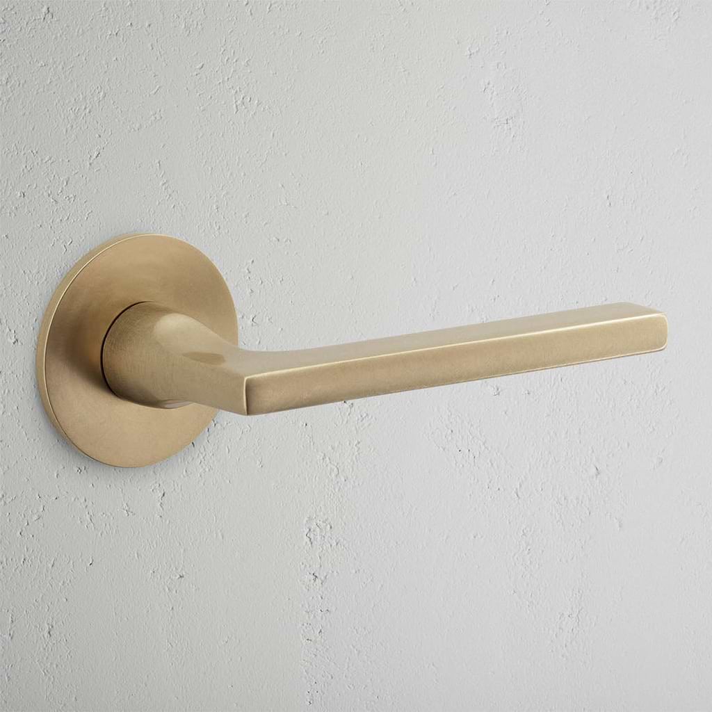 Clayton Flush Rose Sprung Door Handle Antique Brass Finish on White Background  