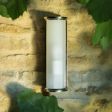 Medium wall light with polished nickel finish and fluted glass shade, mounted on a stone wall.