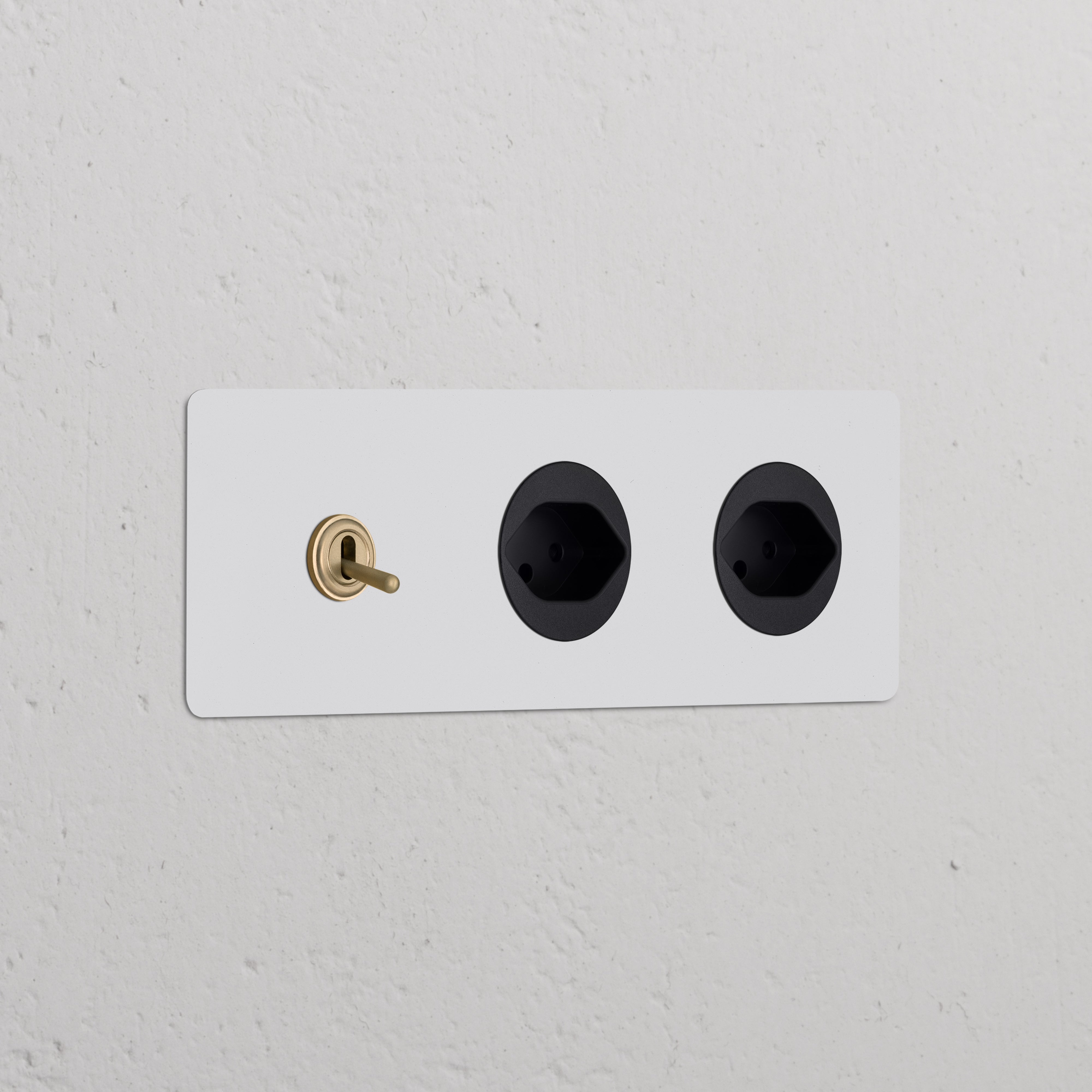 Triple toggle switch with 2 Swiss Type J power modules in paintable antique brass black on a white wall.