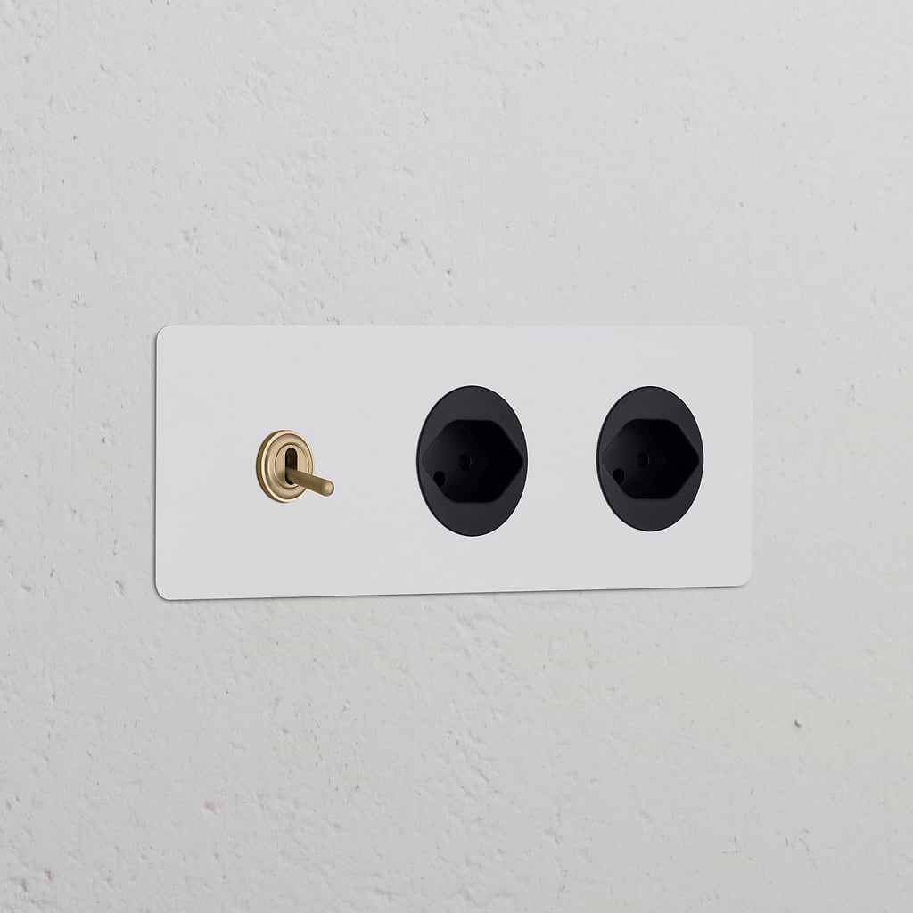 Triple toggle switch with 2 Swiss Type J power modules in paintable antique brass black on a white wall.
