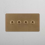 Four-Toggle Double Switch in Rich Antique Brass on White Background