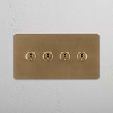 Four-Toggle Double Switch in Rich Antique Brass on White Background