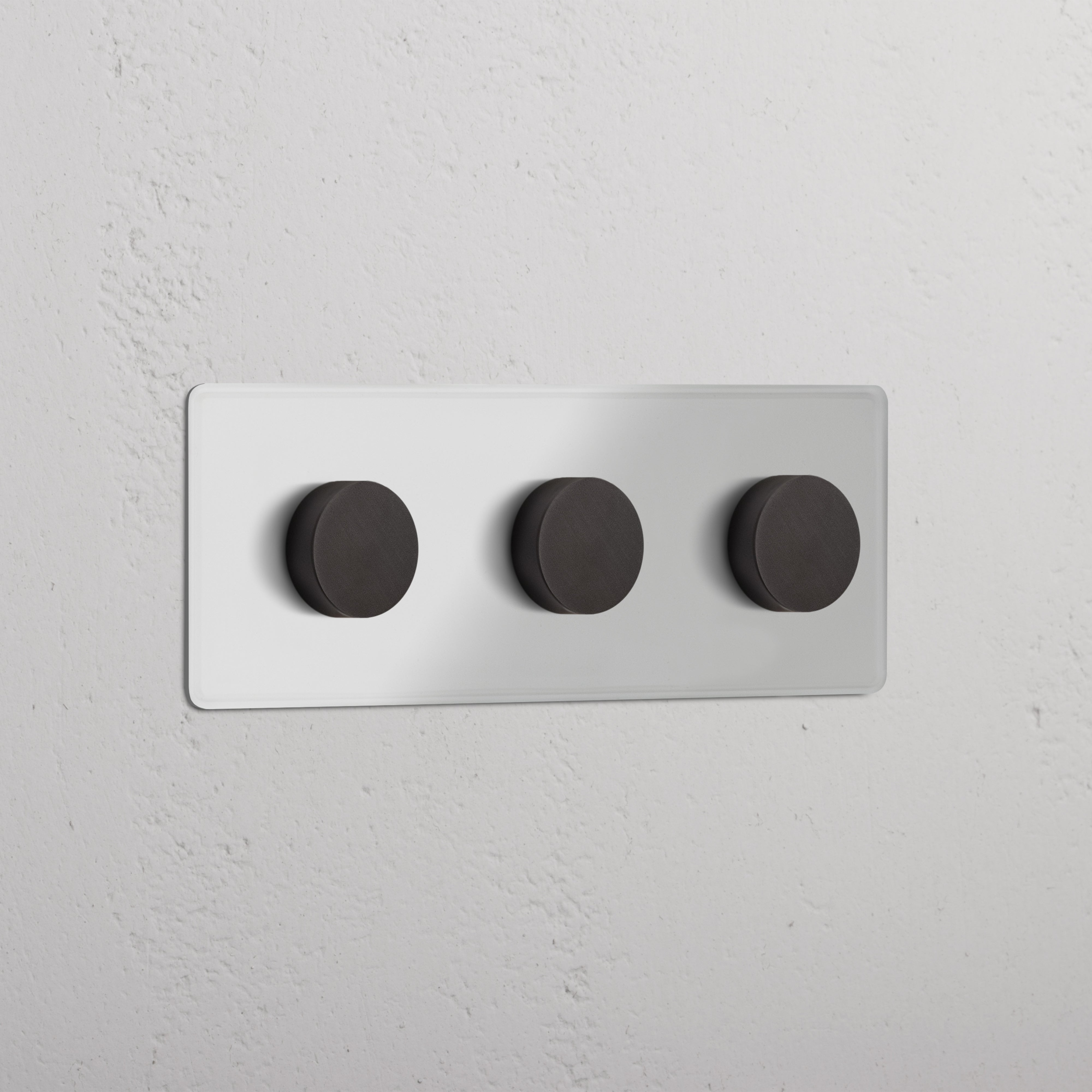 Plaque murale triple finition bronze transparente avec trois variateurs multidirectionnels, montée sur un mur.