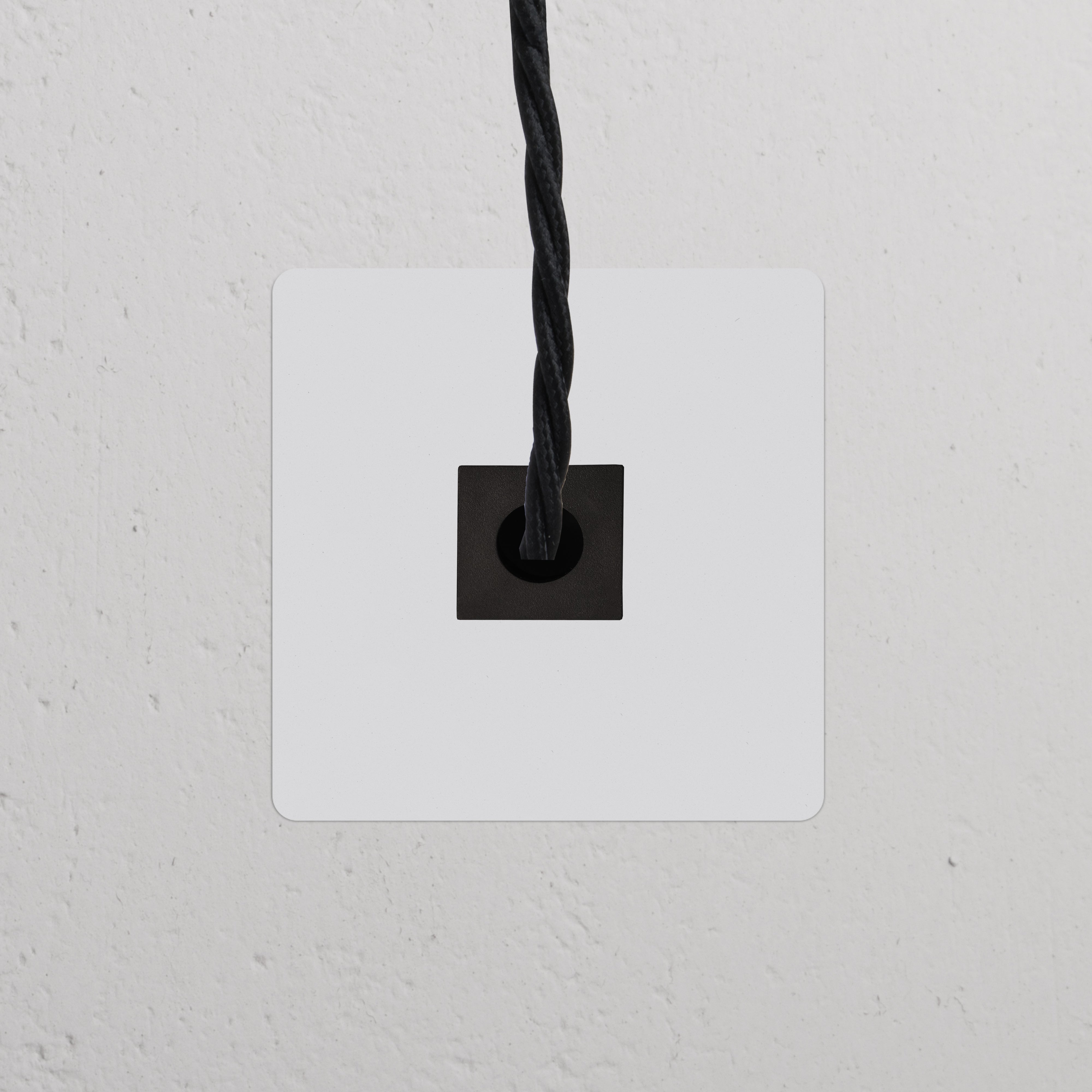 Sortie de Câble Noire (Plaque Simple) pour entrée de câble, faisant partie des Prises & Modules Simples, montée sur un mur.