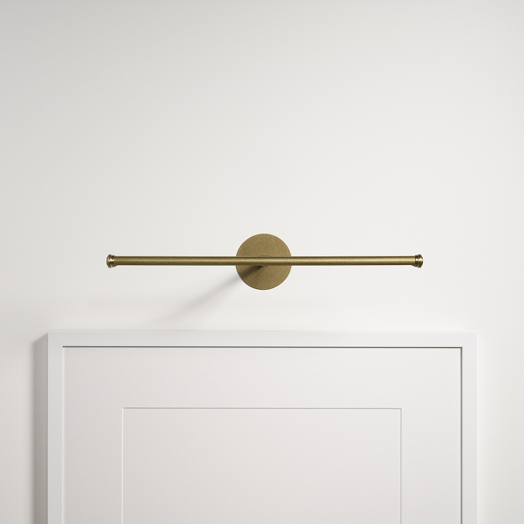 L'applique pour tableau Taylor 400 mm en laiton antique met en valeur les œuvres d'art sur un mur blanc uni.