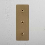 Antique Brass Triple Toggle Switch with Vertical Orientation on White Background