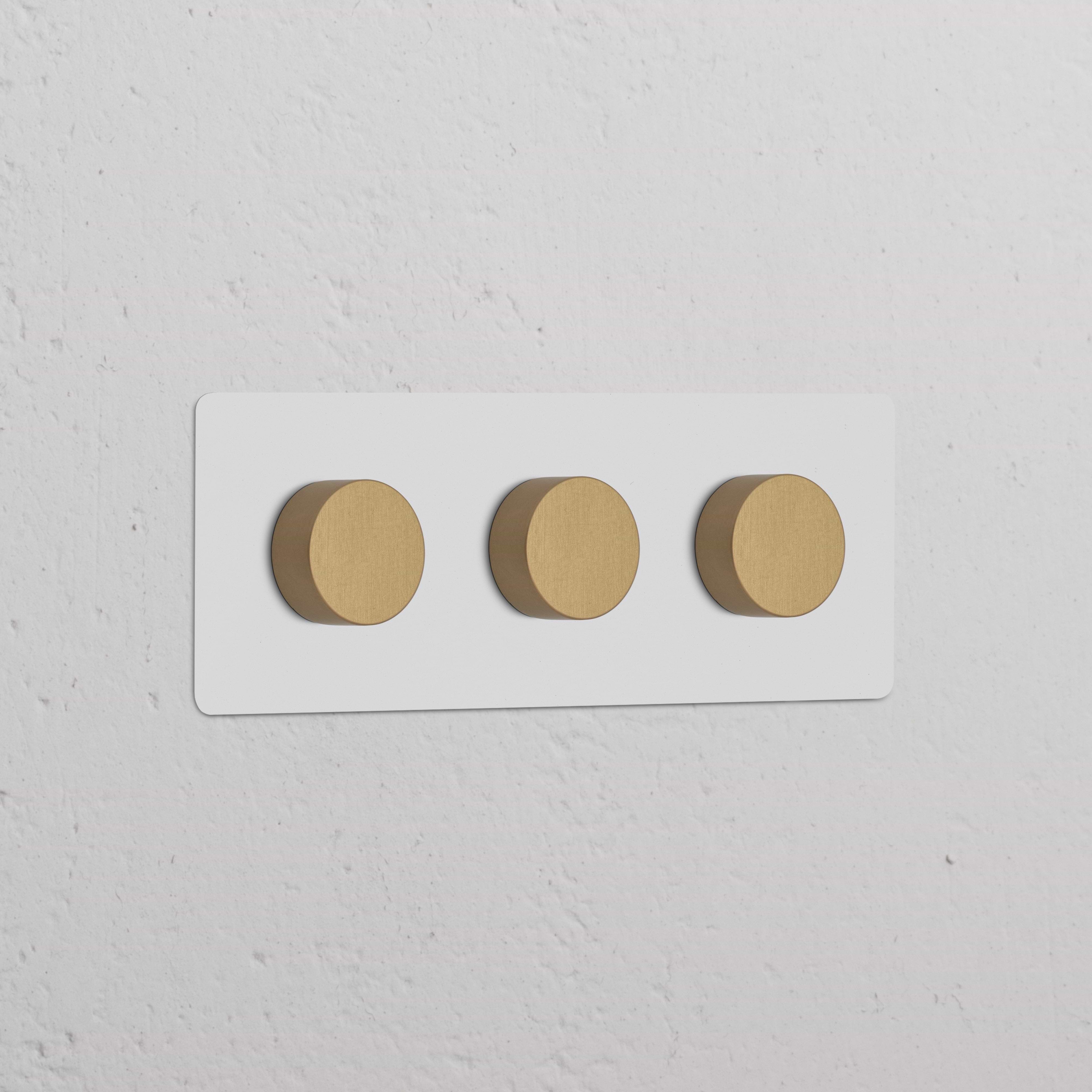 Plaque triple d’interrupteurs et variateurs en laiton ancien peignable avec trois boutons ronds.