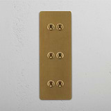 Six Lever Triple Vertical Toggle Switch in Antique Brass on White Background