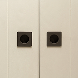 Gros plan de Regent Petite Poignée Encastrée Porte Galandage Bronze sur des portes d'armoires beiges.