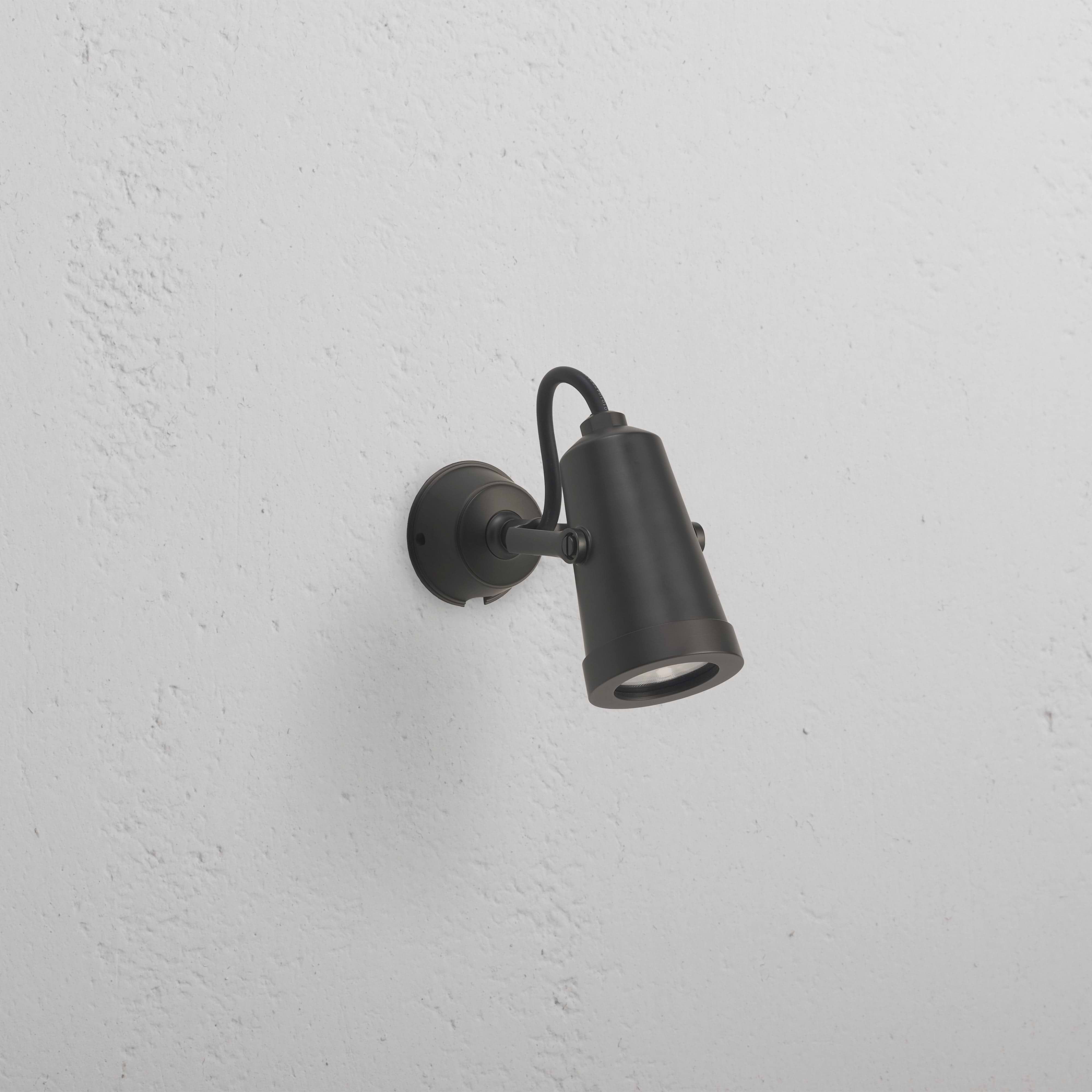 Cambridge Projetor de parede 24 V para exterior em bronze, montado na parede branca e inclinado para baixo.