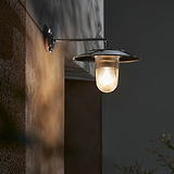 Luminária de parede média 'Kensington' em vidro nervurado com acabamento em níquel polido, montada em uma parede texturizada.