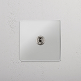 Conveniente interruptor articulado individual retrátil em Níquel Polido Transparente - Ferramenta de gestão de luz prática em fundo branco