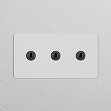 Interruptor articulado de três vias duplo em bronze pintável montado em parede branca.