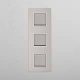Interruptor basculante triplo vertical em Níquel Polido Branco em fundo branco