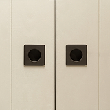 Close-up of minimalist white sliding doors with bronze Regent Recessed Small Pull handles.