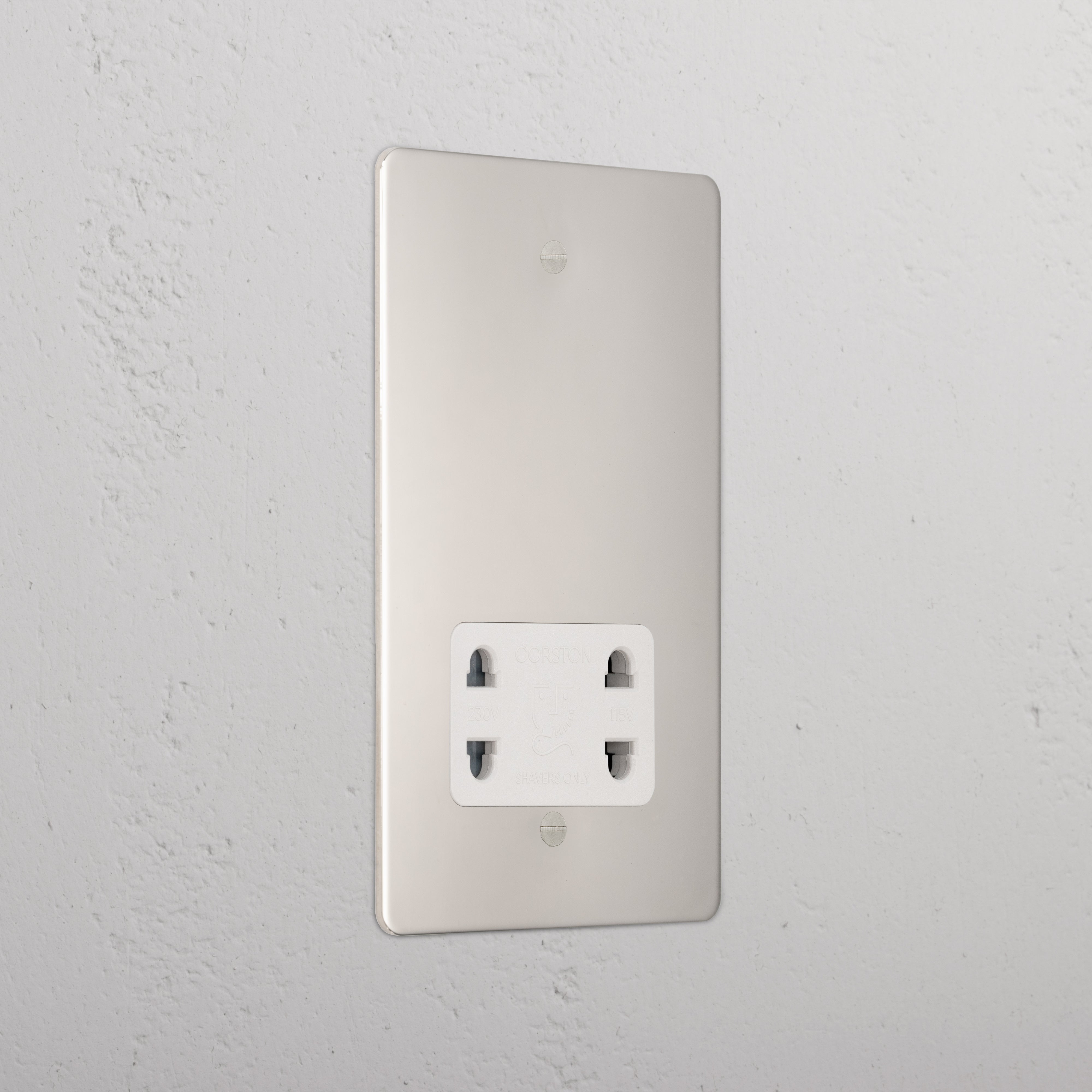 Polished nickel shaver socket with white insert on grey wall. 