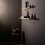 Antique Brass Brixton Shelf Bracket 200mm supporting a wooden shelf and  a longer shelf beneath both fixed on a black matte wall with Decoratives on shelves. viewing the image on the right wall. 