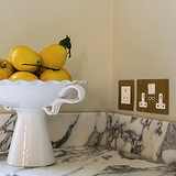 Antique Brass White 5A light socket in kitchen wall on top of marble counter top next to white fruit basket with lemons 